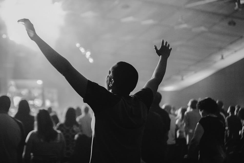 A silhouette with arms lifted in a crowd, in black and white