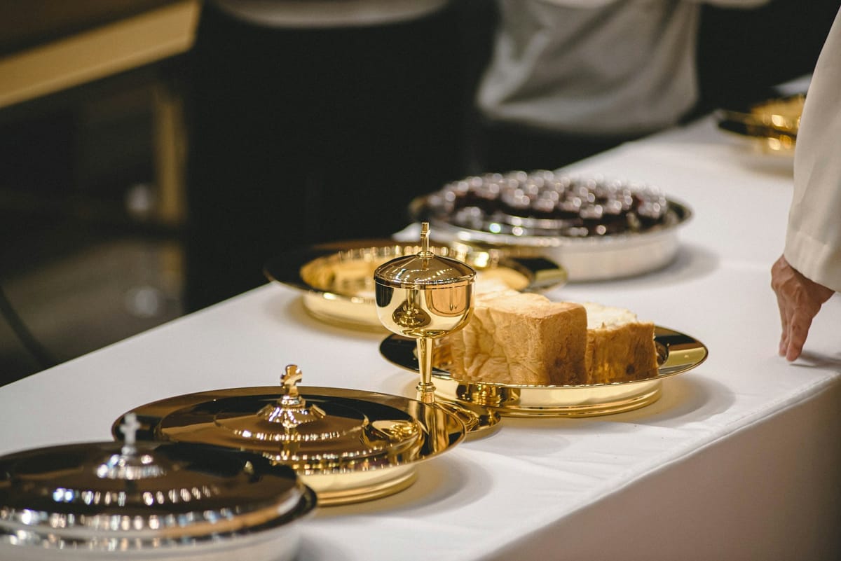 Communion bread and covered gold cups on a white cloth