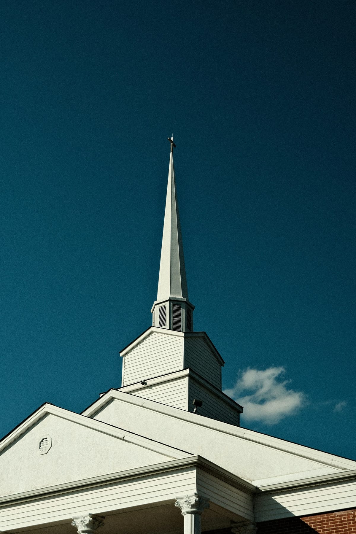 The white steeple of the church against a clear blue sky